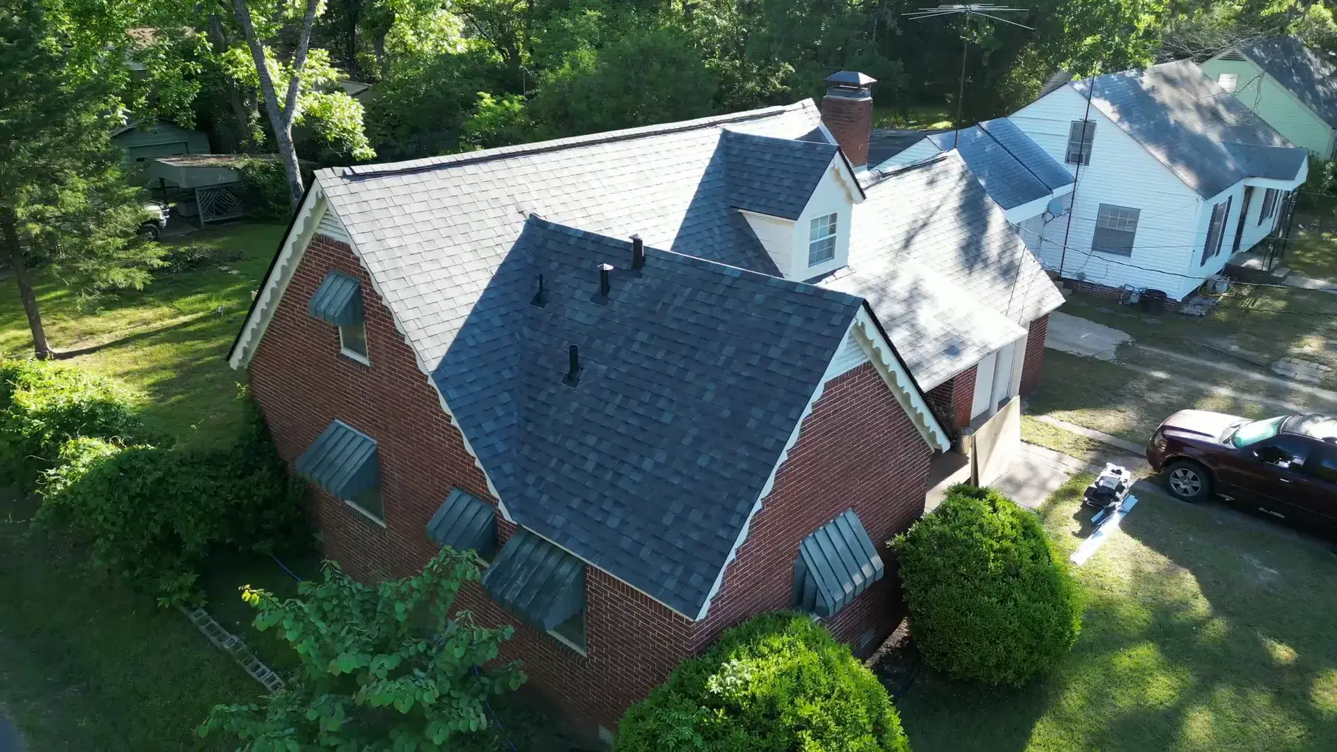 Red brick two-story home with a new dark shingle roof and detailed roof-to-brick trim